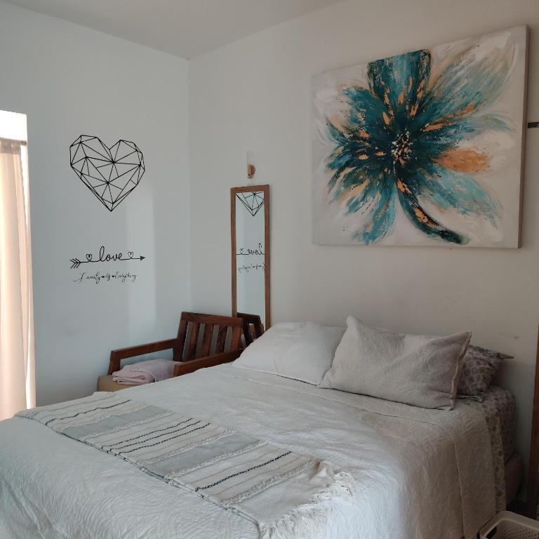 1 dormitorio con 1 cama y una pintura en la pared en Agradable departamento para descanso o home office. en Cabo San Lucas