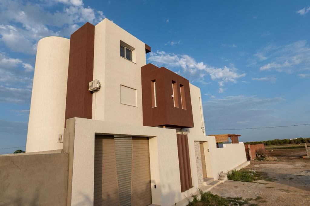 a white and brown building with a sky at Villa Dhaouia torki in Kelibia