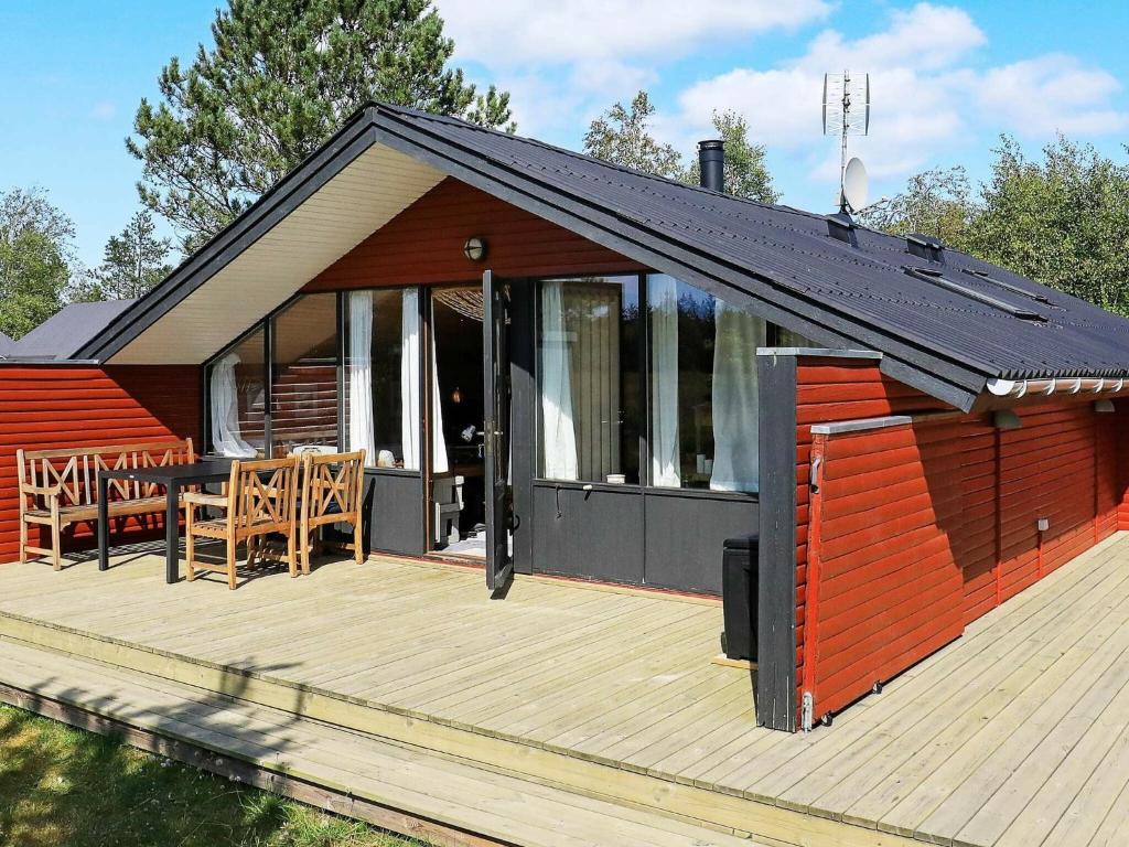 a small house with a wooden deck with a table at 6 person holiday home in Ålbæk in Ålbæk