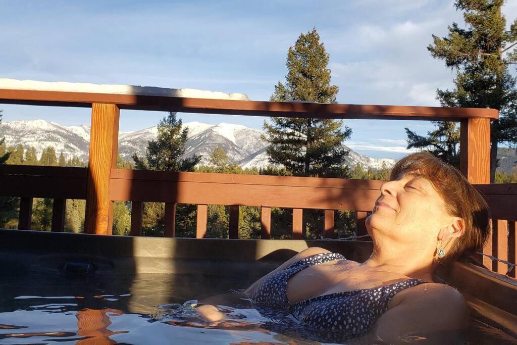Una donna in una vasca idromassaggio con le montagne sullo sfondo di Hot Tub-Mountain View-Secluded-Entire Private Floor a Seeley Lake