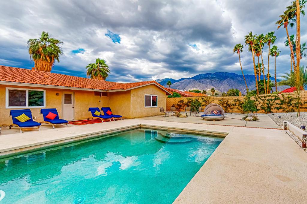 uma piscina com cadeiras e uma casa em Tamarisk Mountain View #5627 em Palm Springs