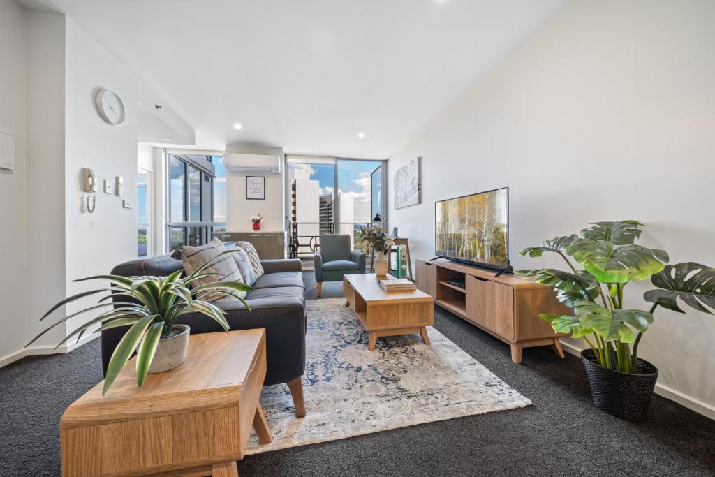 a living room with a couch and a tv at Glorious Central Canberra 1-Bed with Pool & Sauna in Canberra