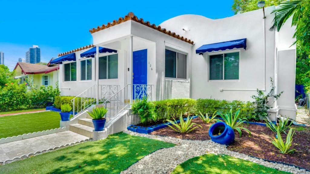 een wit huis met een blauwe deur en een tuin bij Casa Wynwood Miami in Miami