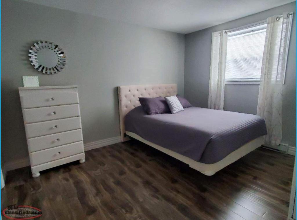 a bedroom with a bed and a dresser and a mirror at Elegant Private Room in Oshawa
