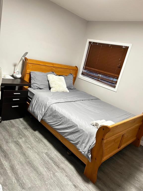 1 dormitorio con cama de madera y ventana en Cozy room D, en Kitchener
