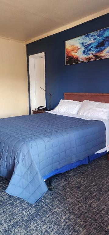 a large bed in a room with a blue wall at Relax Inn Rural Retreat- Marion - Atkins in Rural Retreat