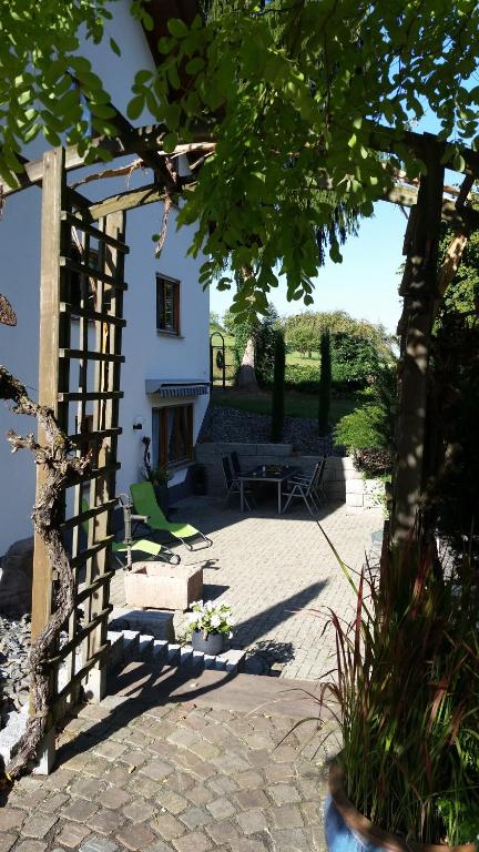 a garden with a white building and a bench at Ferienwohnung Hotte´s Hütte in Ettenheim