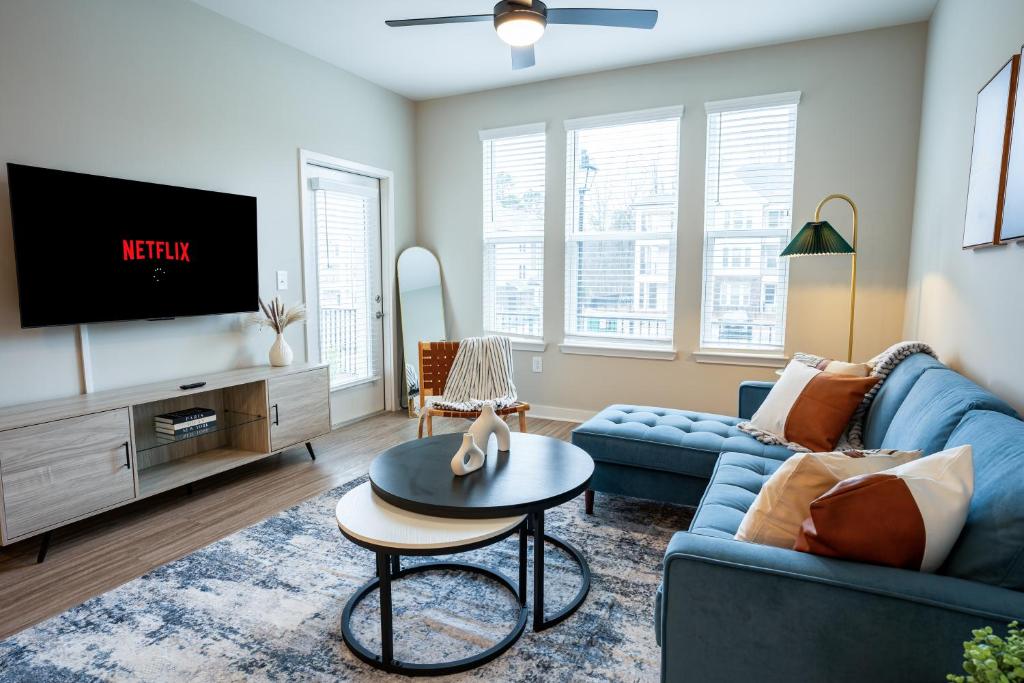 uma sala de estar com um sofá azul e uma televisão em Modern Brand New 3BR 2B Apt in Heart of Athens em Athens