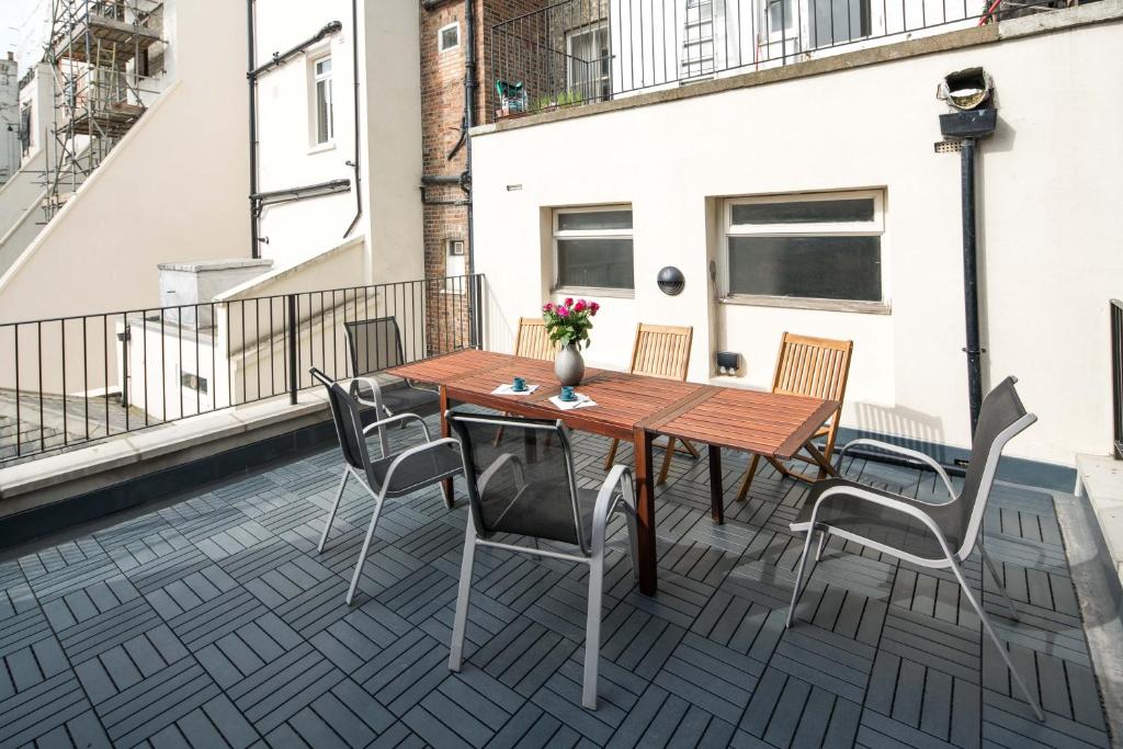d'une terrasse avec une table et des chaises en bois sur un balcon. dans l'établissement Roof Haven at Kensington Mews, à Londres