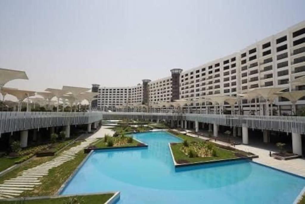 a large hotel with blue pools in front of a building at Unique duplex hotel apartment pool view in Cairo