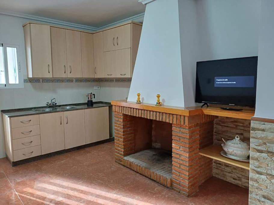 cocina con chimenea y TV de pantalla plana en Casa Rural la Ruta del Vino Zarcilla de Ramos, en Lorca