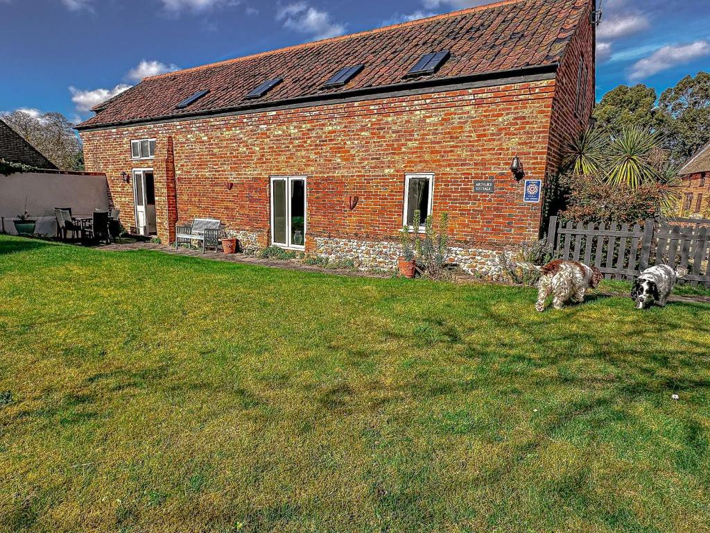 a brick house with two dogs in front of it at Arthurs Cottage - rural hideaways in Norfolk in Edingthorpe