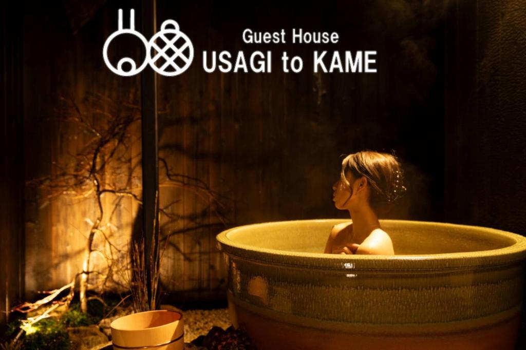 a woman sitting in a bath tub with a sign at 旅宿うさぎとかめ Guest House USAGI to KAME 近江八幡中心地 ヴォーリズ建築好きにお勧め in Hachiman