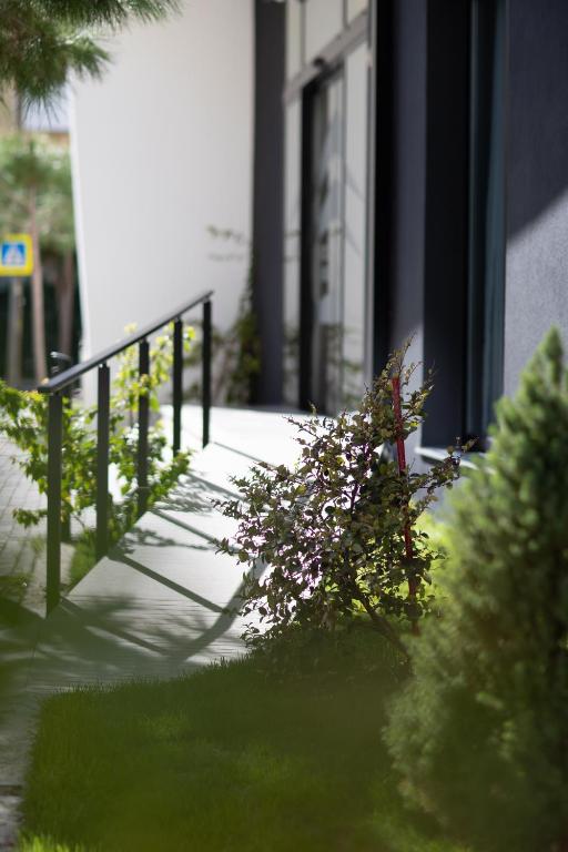 a sidewalk with a railing and a bush with flowers at La Onda Hotel Durres in Durrës