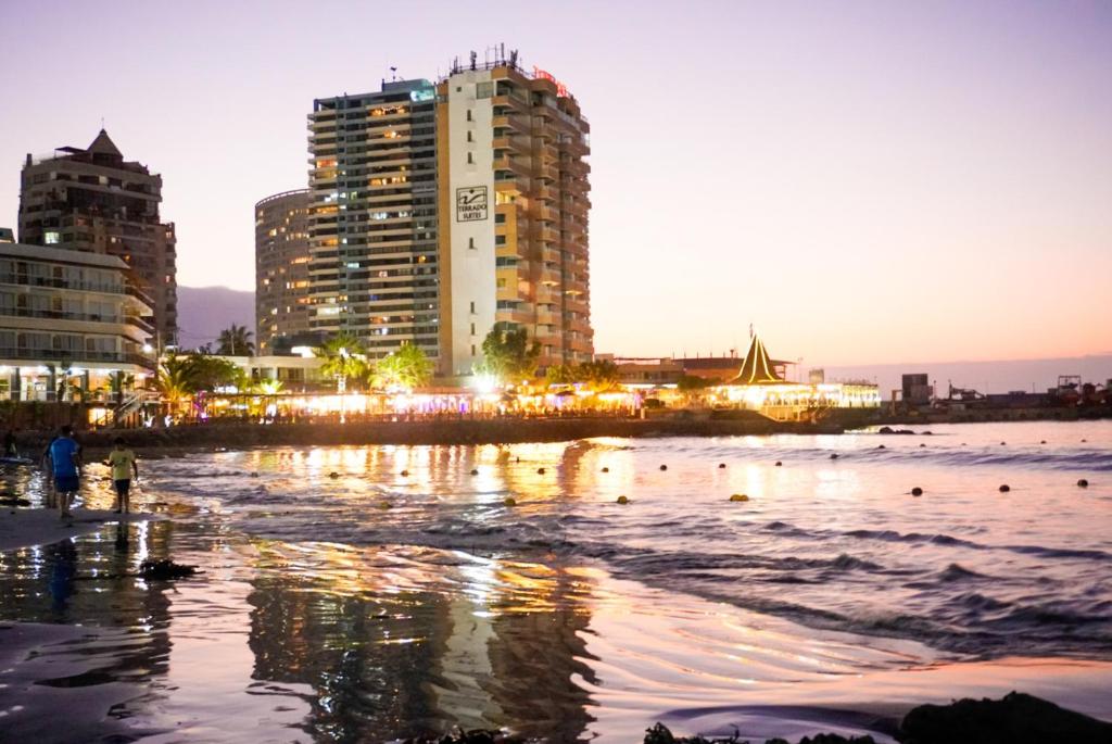 a city skyline with buildings and the ocean at night at Edificio Royal Marine in Iquique
