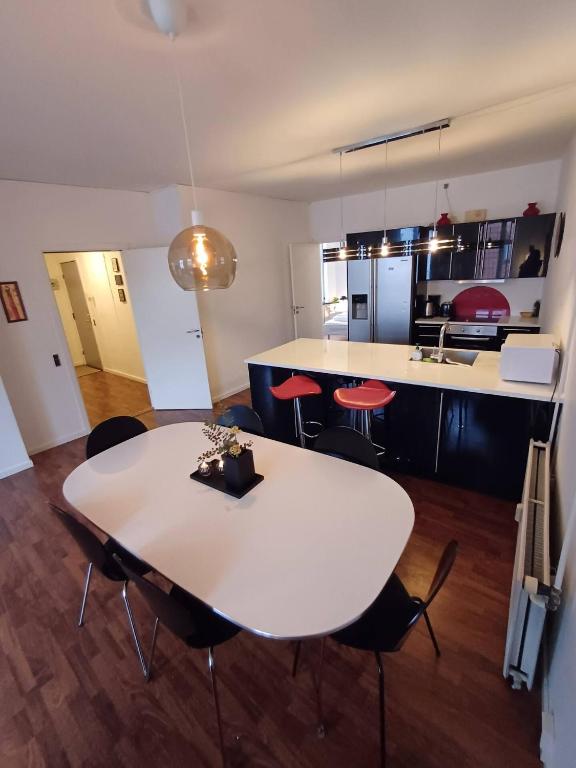 a white table and chairs in a room with a kitchen at Stylish Apartment On Pedestrian Street Randers in Randers