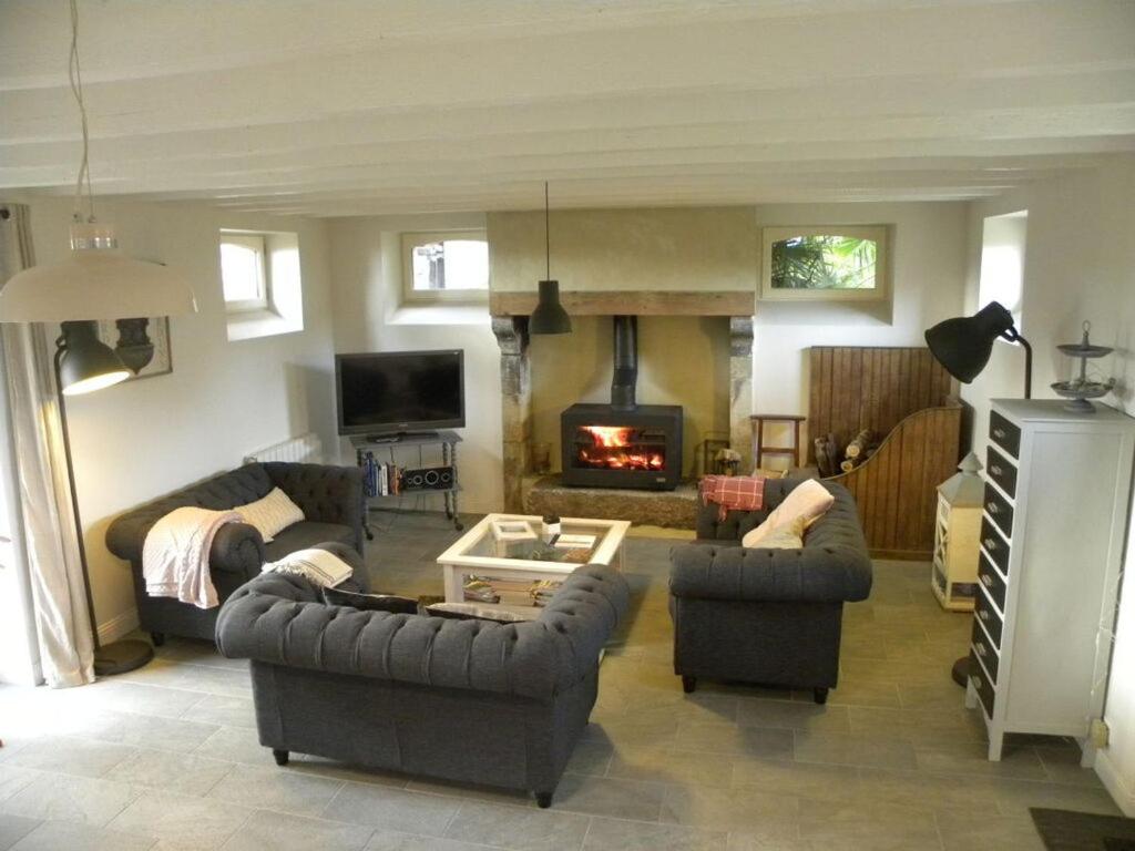 sala de estar con 2 sofás y chimenea en Holiday home La Jardinerie, en Aumeville-Lestre