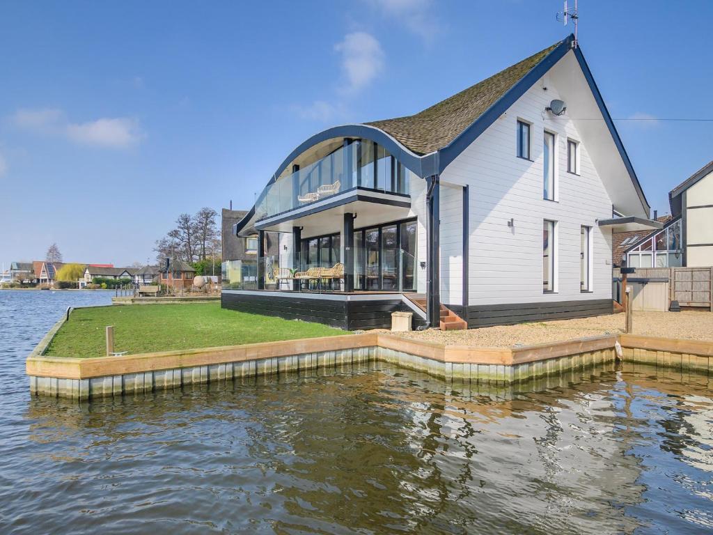 a house on the water next to a body of water at Bide-a-wee in Wroxham
