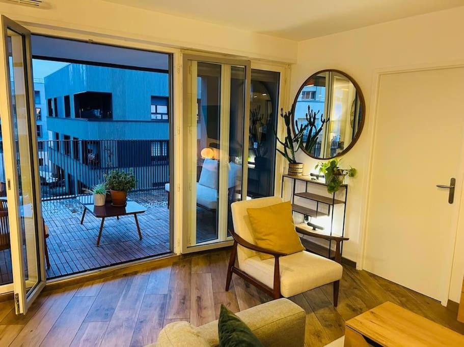 Il comprend un salon avec une chaise et un balcon. dans l'établissement Sublime Appartement Proche JO 2024, à Saint-Denis