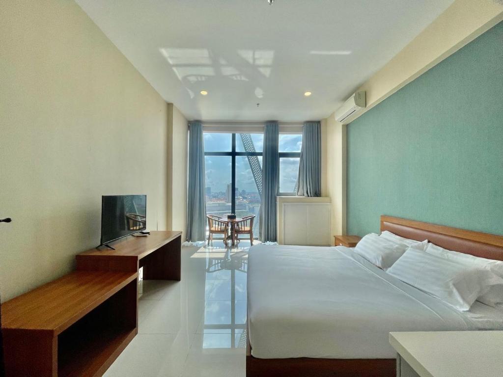 1 dormitorio con 1 cama, TV y mesa en Zhong Xin Hotel en Phnom Penh
