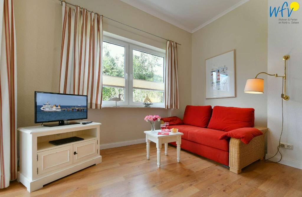 a living room with a red couch and a tv at Haus am Hövt - Ferienwohnung 1 in Göhren