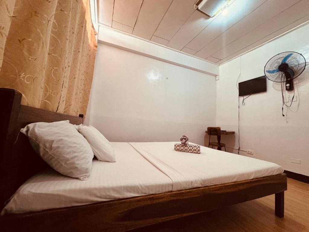 Cama en habitación con ventilador en la pared en Duchess Sophia's Pension en Puerto Princesa