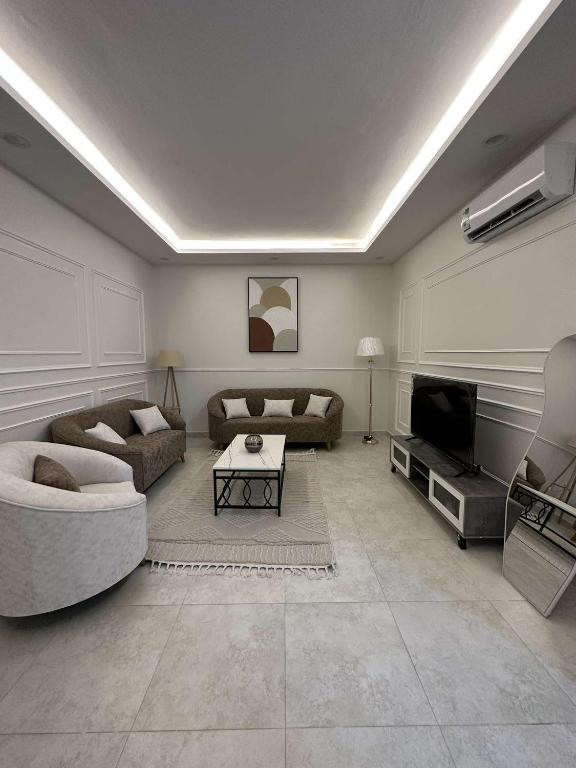 Sala de estar con 2 sofás y TV en وحدة سكنية مع كراج خاص للسيارة, en Bīshat Mushayţ