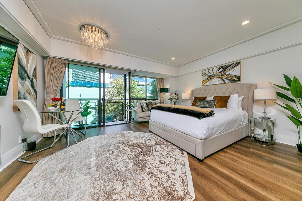 a bedroom with a bed and a couch and windows at Viaduct's Hidden Gem in Auckland