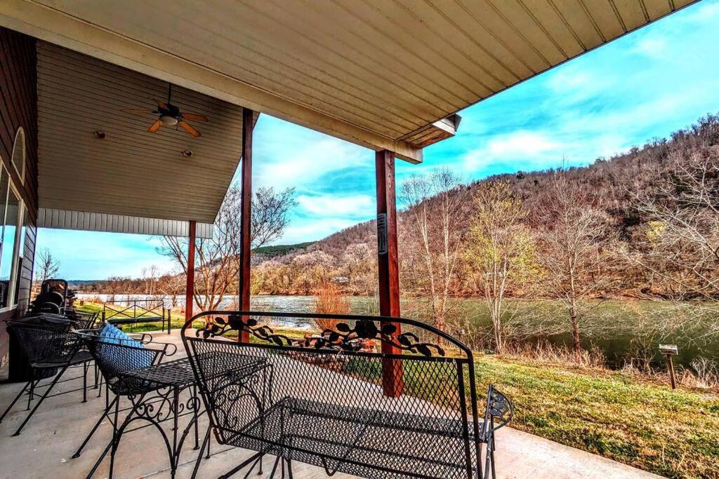 a porch with chairs and a table with a view of a mountain at Fishing Cabin on White River w/ public boat ramp! in Norfork