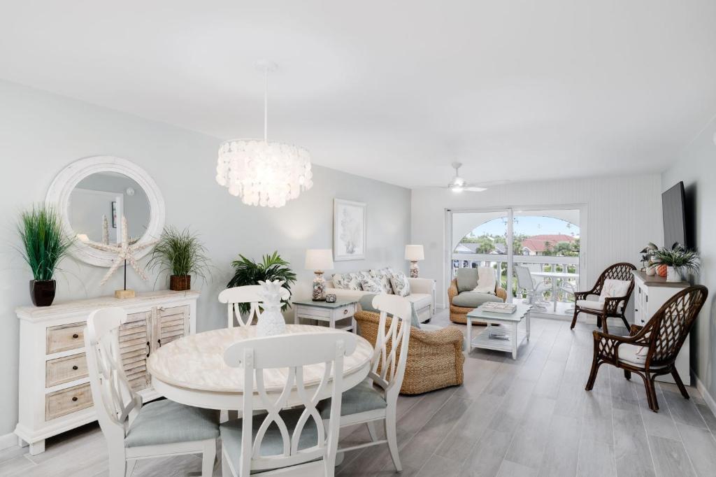 a white living room with a table and chairs at Gorgeous Top Floor Beach Condo at Breakers West in Sanibel