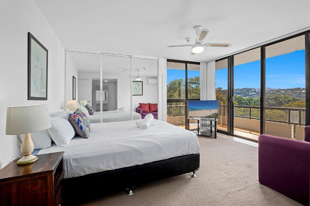 a bedroom with a large bed and a balcony at Pacific Towers Beach Resort in Coffs Harbour