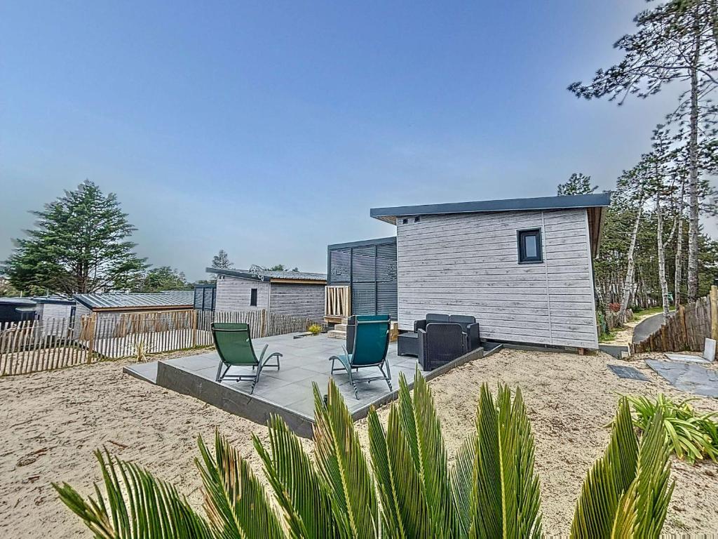 2 chaises assises sur une terrasse en face d'une maison dans l'établissement Chalet haut de gamme - 6 pers - Piscine chauffée - Proche plage - Jullouville - FR-1-361-518, à Jullouville