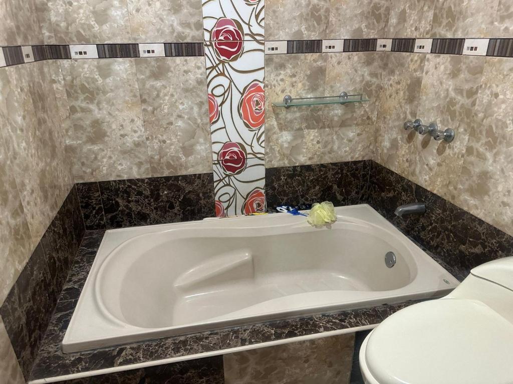 a bath tub in a bathroom next to a toilet at Hotel Elegant in Cajamarca