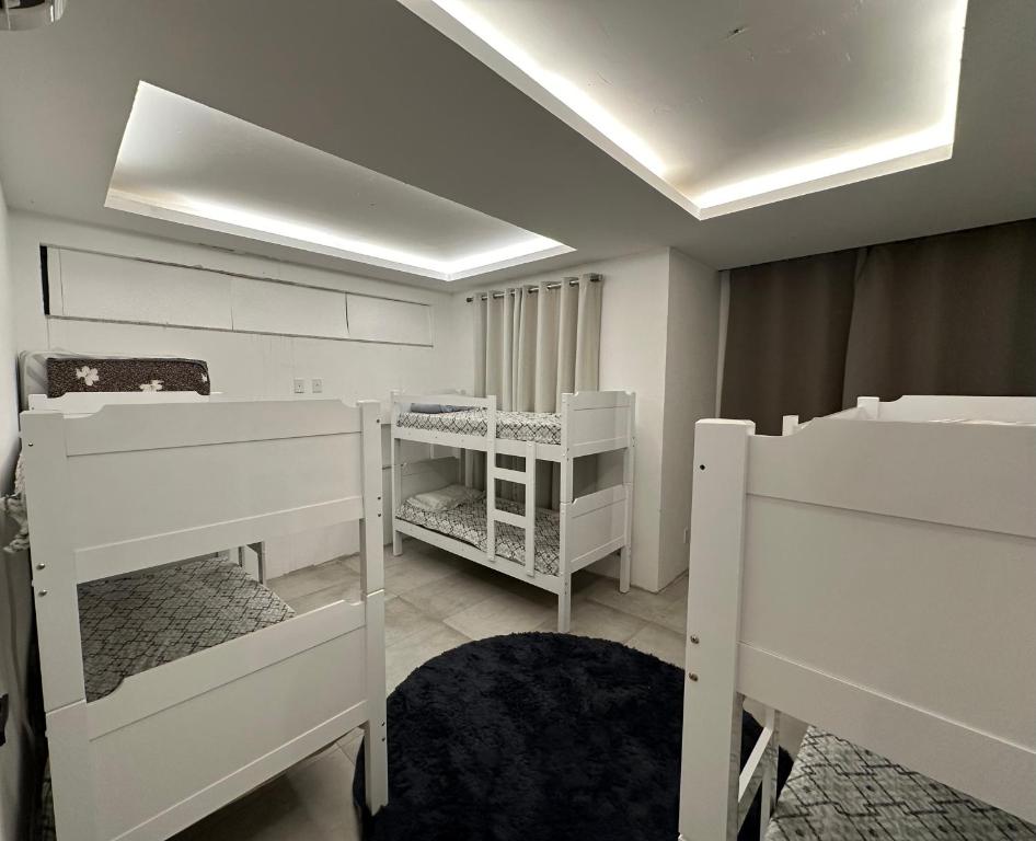 Pokój z białymi łóżkami piętrowymi i sufitem w obiekcie Casa Conteiner w mieście Itaboraí