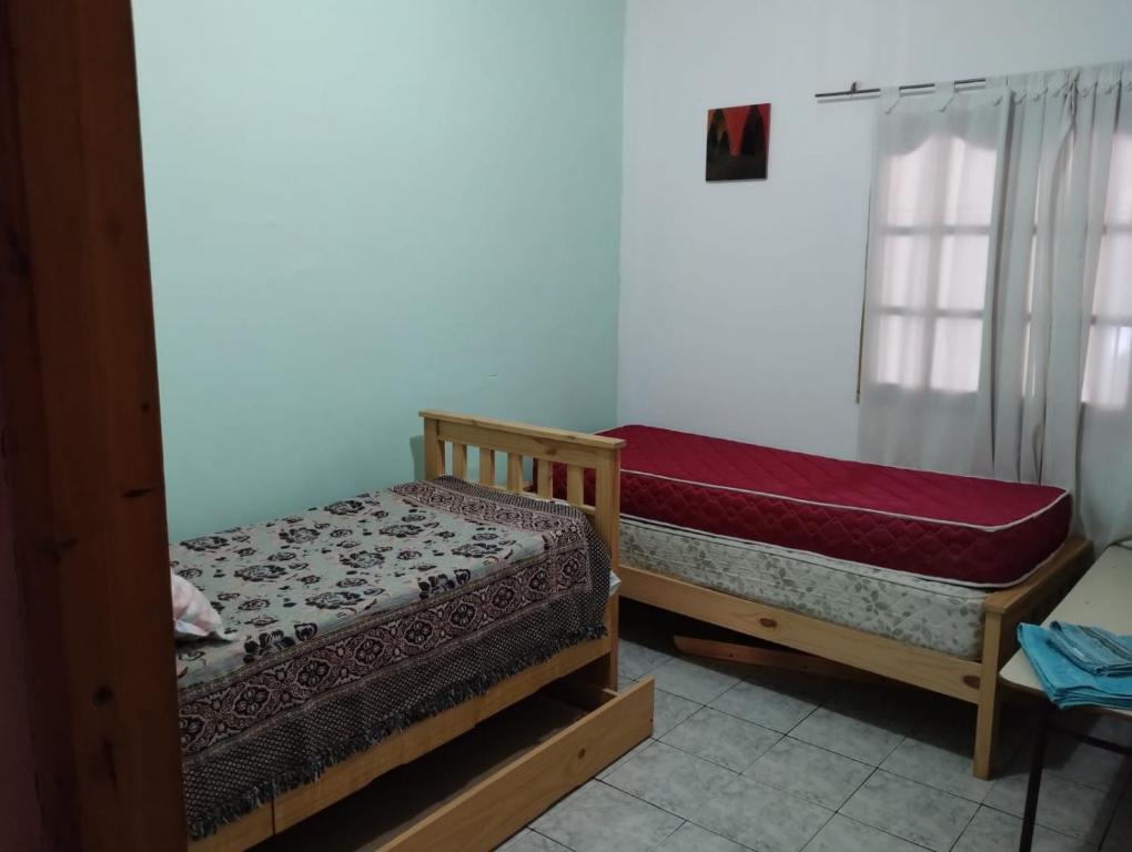 two beds sitting in a room with a window at Departamento West in Las Heras