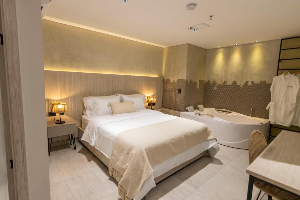 a bedroom with a large bed and a bath tub at Sonata 44 Hotel Laureles in Medellín