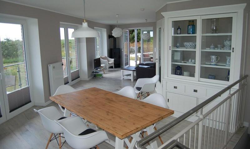 a living room with a wooden table and white chairs at Haus Kiek in't Watt Ferienwohnung Deichrausch in Juist