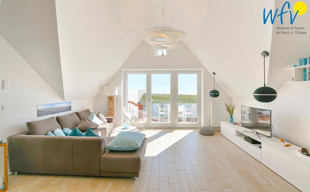 a living room with a couch and a large window at Haus Kiek in't Watt- Ferienwohnung Quartier 7 Ost in Juist