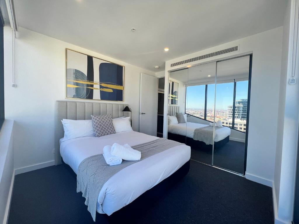 a bedroom with a large white bed and a balcony at Samma Flagstaff Luxury Apartments in Melbourne