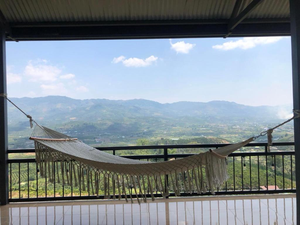 a hammock hanging from a window with a view at Doi Hoa Do Homestay in Bao Loc