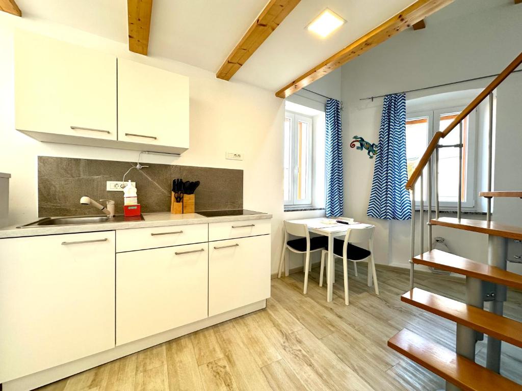 a kitchen with white cabinets and a table at Old Piran Starfish in Piran