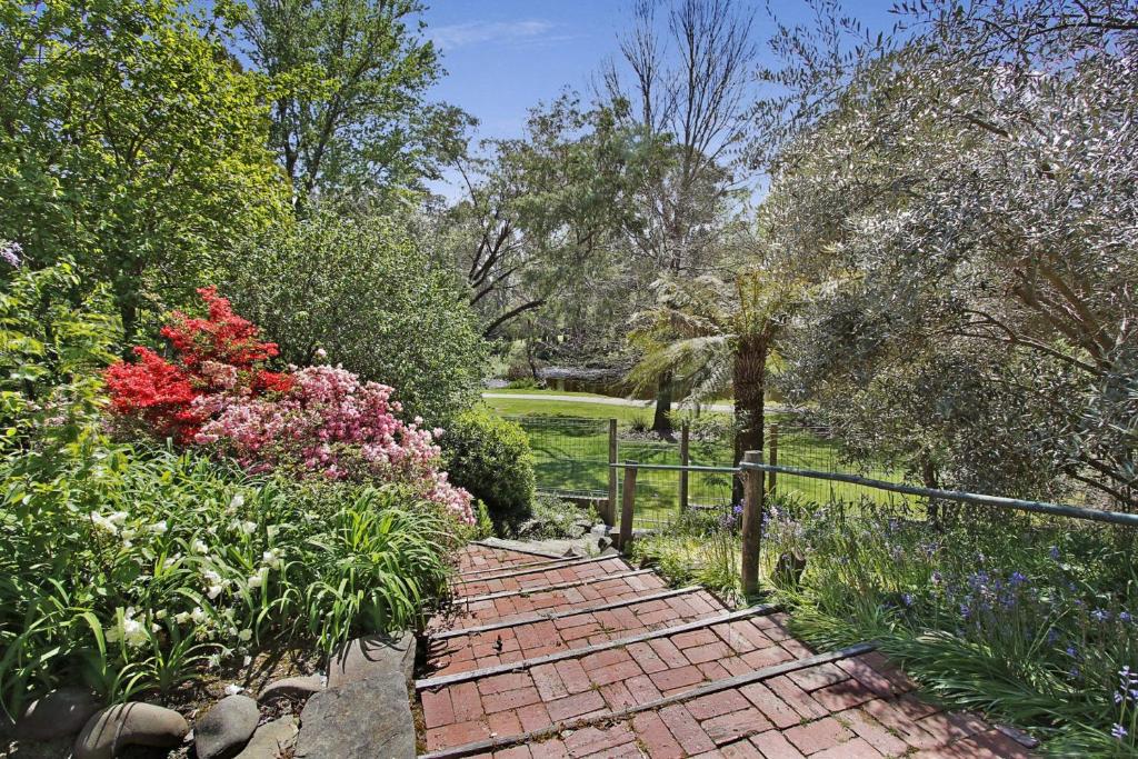 een stenen loopbrug in een tuin met bloemen bij Warrina - Overlooks Ovens River and five minute walk into town in Bright