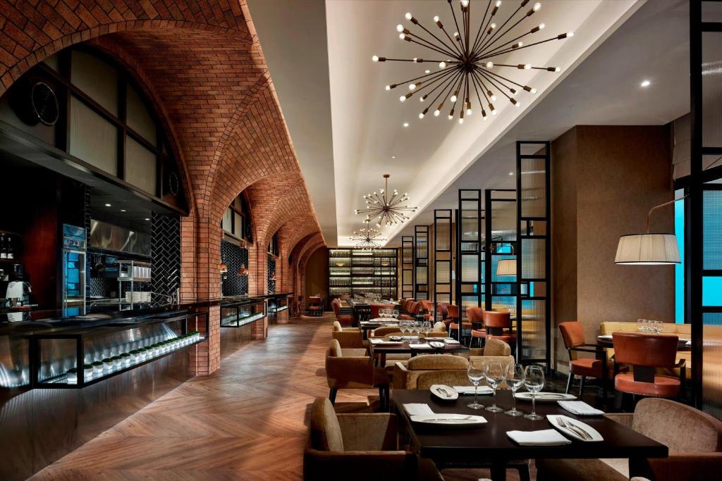 A brick-arched restaurant offers formal table seating beside a bar and display counter.