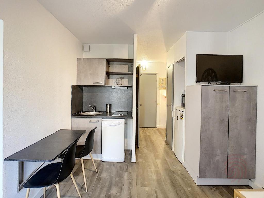 une cuisine avec une table et des chaises dans une pièce dans l'établissement Charmant F2 avec Balcons, Proche Thermes, Animaux Acceptés, Wifi, Ascenseur, Parking Gratuit - FR-1-451-206, à Lamalou-les-Bains