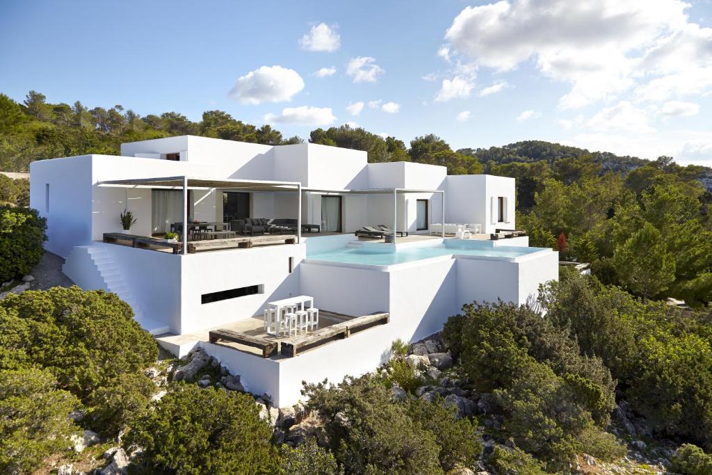 una casa blanca en una colina con árboles en Villa Na Xamena Ibiza, en Sant Miquel de Balansat