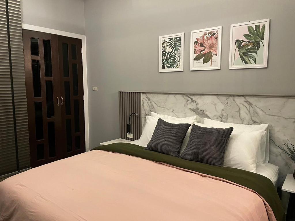 um quarto com uma cama grande com três fotografias na parede em 356 Hostel em Thung Song