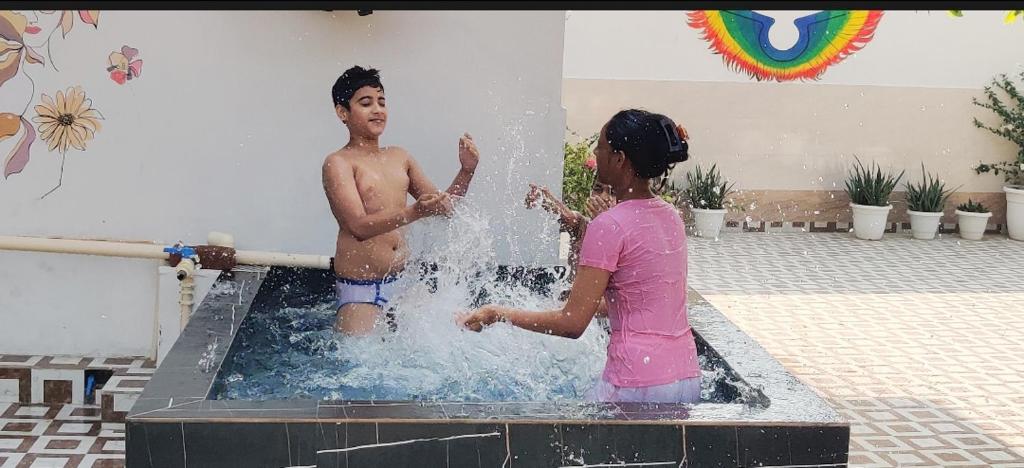 a boy and a girl playing in a fountain at Shobhayan inn in Ayodhya
