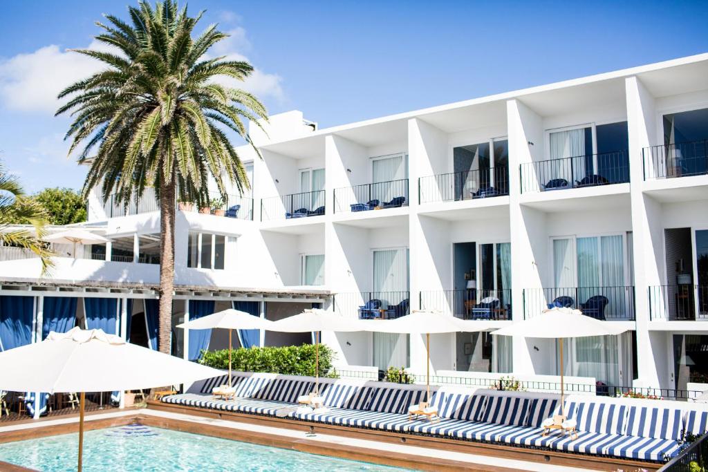 un hotel con piscina, palmeras y sombrillas en Halcyon House en Cabarita Beach