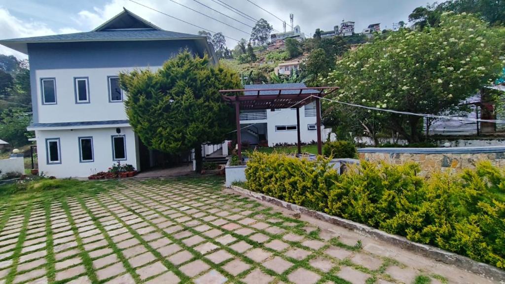 a white house with a roof at Magizham Homestay in Kodaikānāl