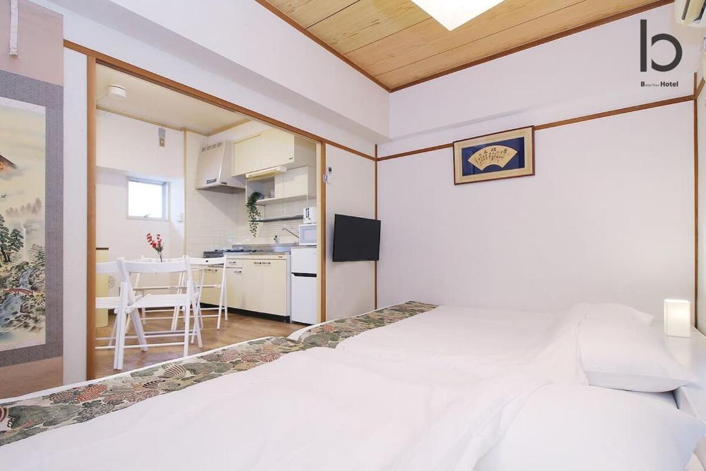 a bedroom with a bed and a kitchen with a table at Dai3Kuboi - 1 BR for 4 ppl mins walk to Peace Park in Hiroshima